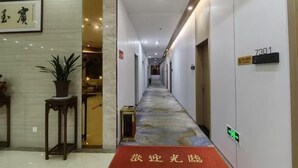 Un couloir d’hôtel avec un sol en marbre, une moquette rouge et une pancarte indiquant le numéro de chambre 7301.