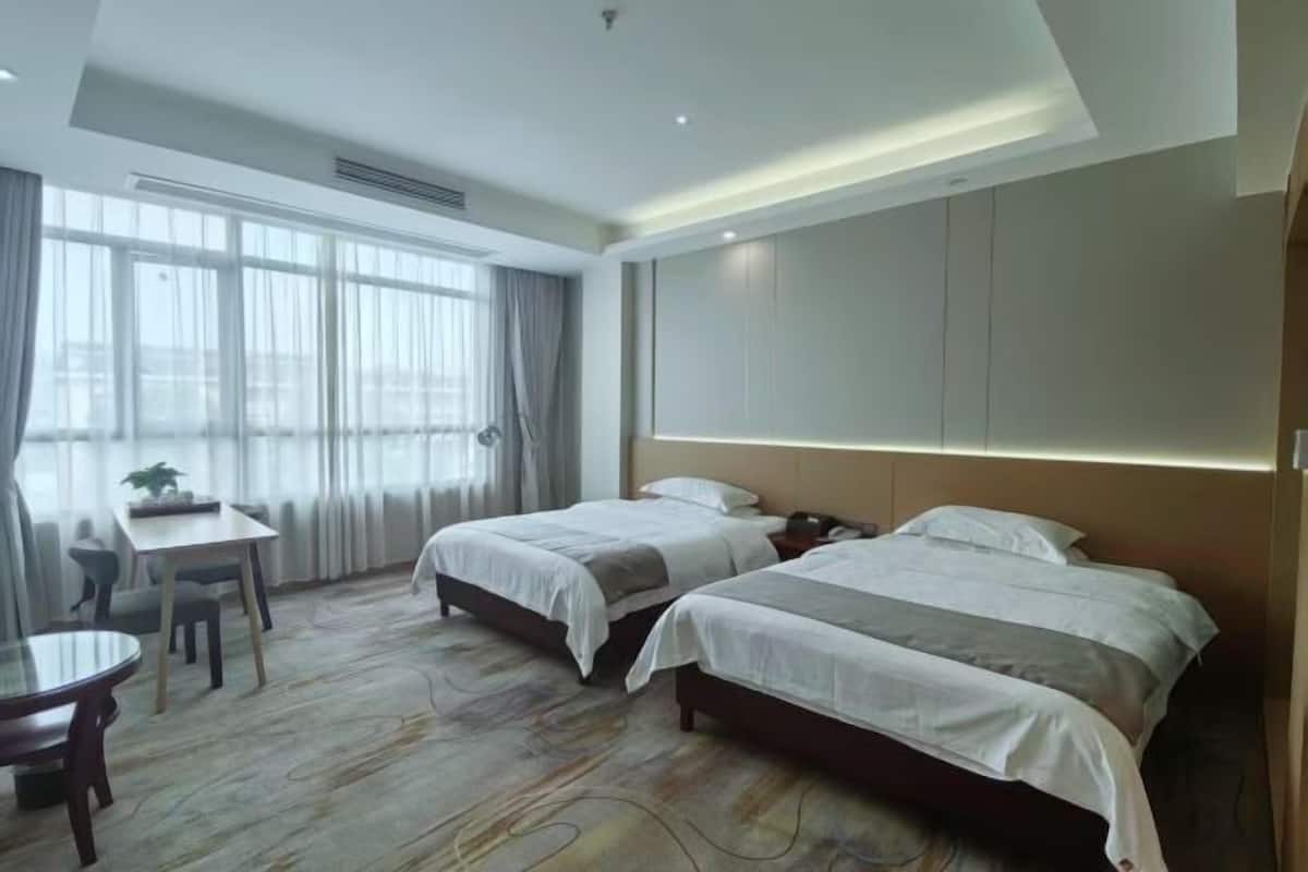 A hotel room with two beds, a desk, and a chair.