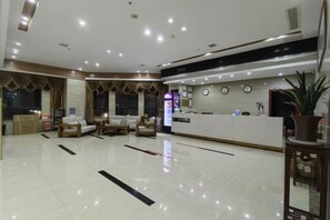 A hotel lobby with a reception desk, seating area, and a large mirror. - Fenghuang Huating Hostel (Guangze)