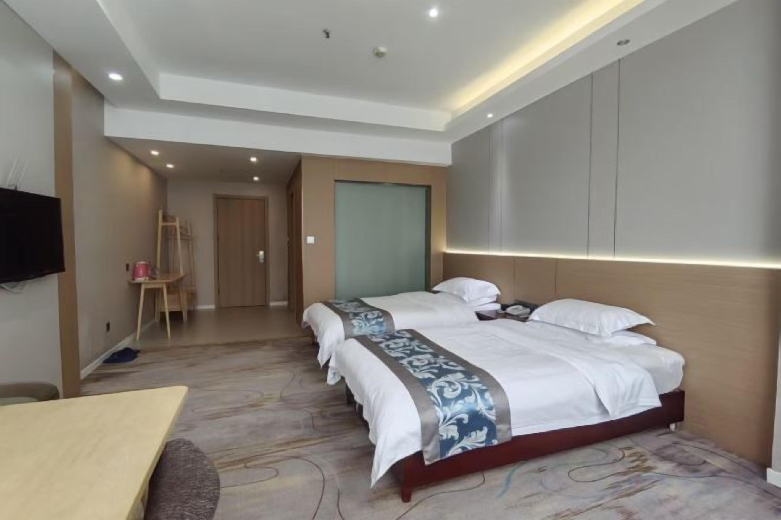 A hotel room with two beds, a flat-screen TV, a desk, and a chair.