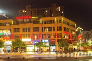 A multi-story building with illuminated signage and storefronts at night. - Fenghuang Huating Hostel (Guangze)