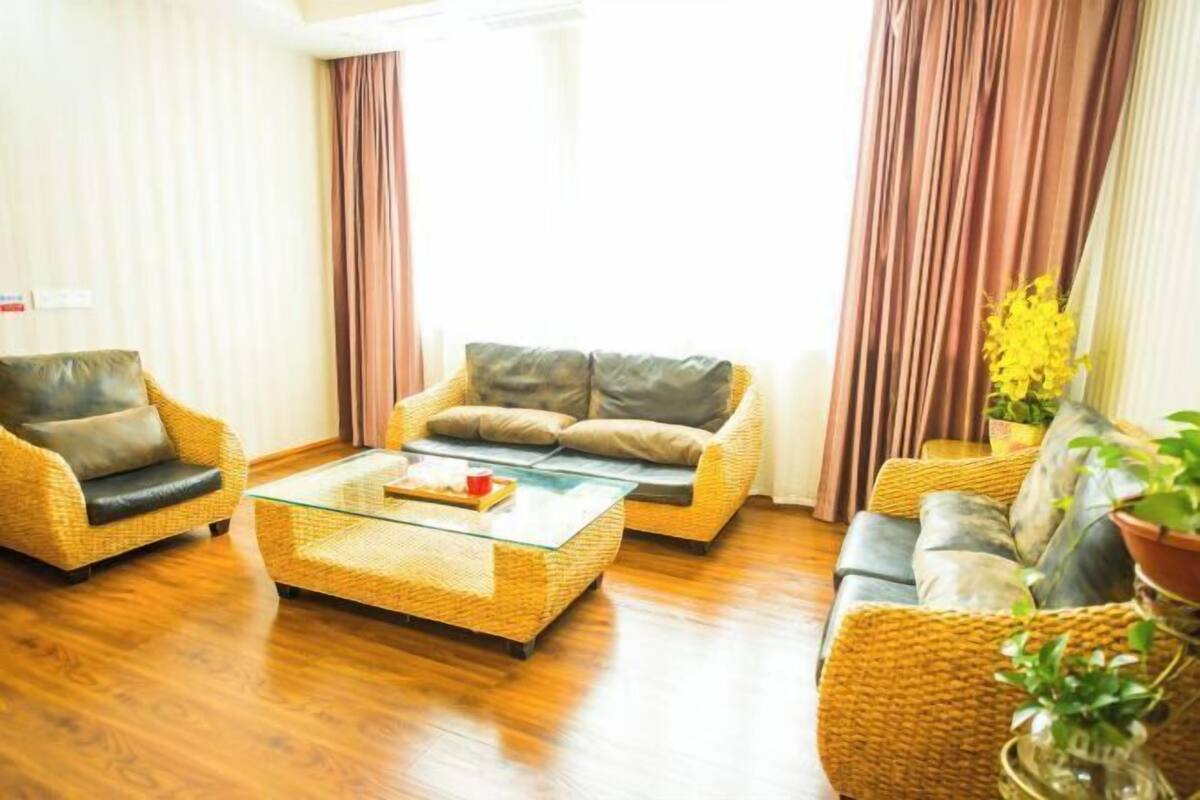 A living room with wicker furniture, a glass coffee table, and curtains.