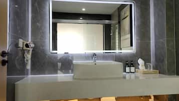 A modern bathroom with a large mirror, a sink, and a vanity area.