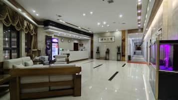 Un vestíbulo de hotel con mostrador de recepción, zona de estar y mostrador de información.