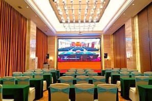 A conference room with rows of chairs, a large screen, and a podium. - Oceanside Hotel (Maoming)