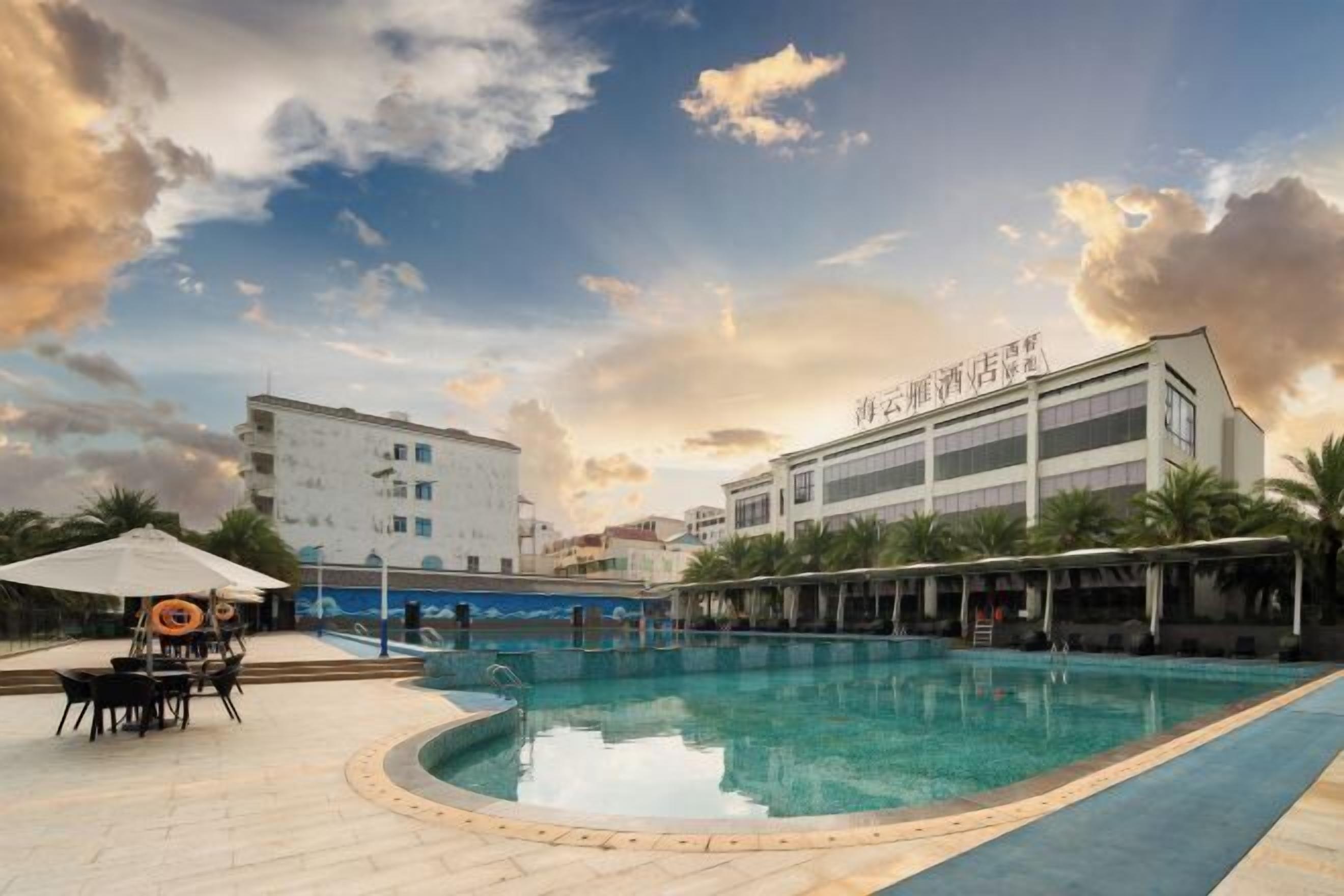 Un espace piscine doté d’un coin salon couvert et d’un bâtiment avec une signalétique.