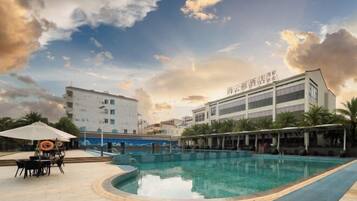Un área de piscina con zona de estar techada y un edificio con señalización.