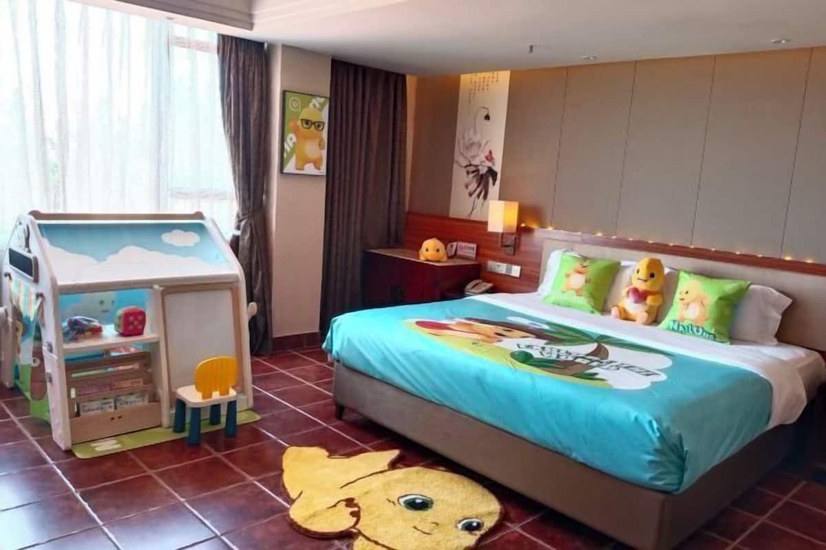 Hotellihuone, jossa on sänky, leikkialue ja ikkuna, jossa on verhot.