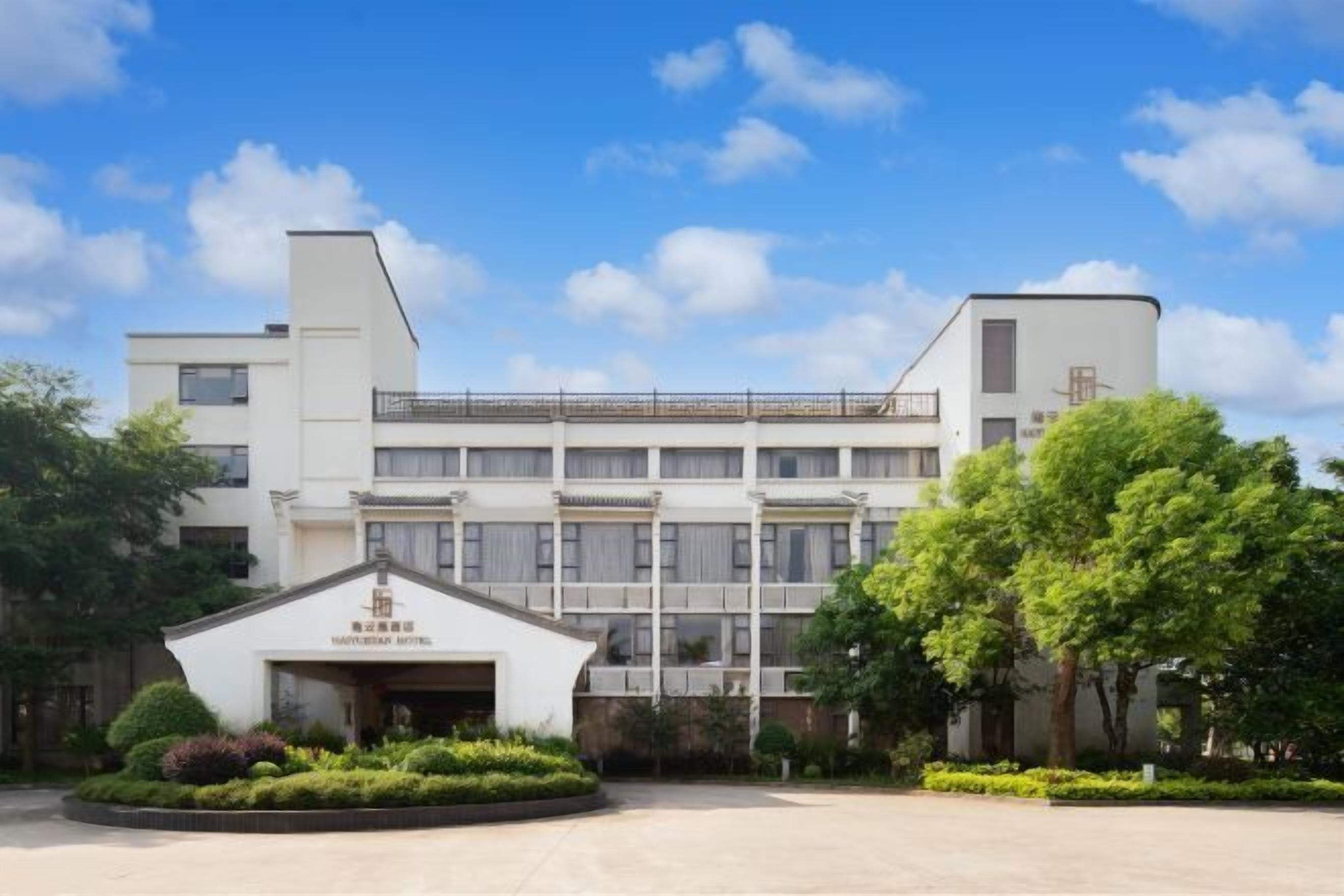 Un hotel moderno con un patio central, una entrada de estilo tradicional y un edificio de varios pisos con tejado plano.