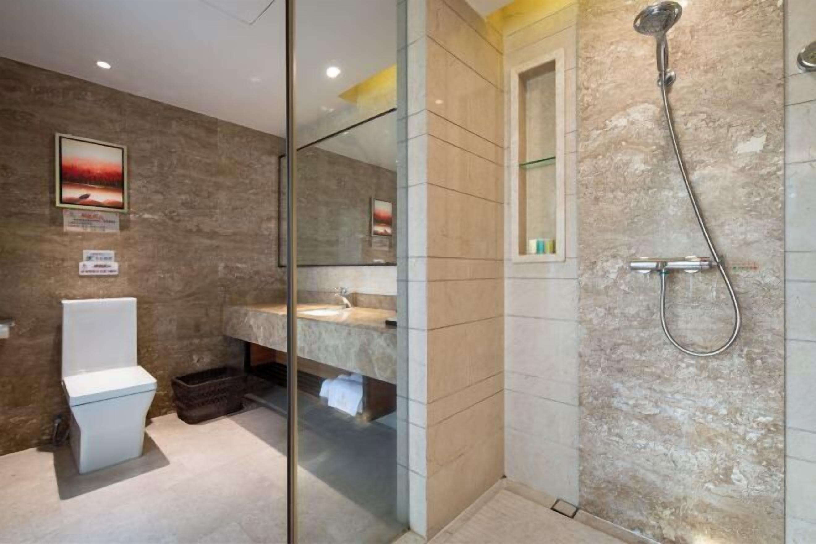 A modern bathroom with a glass shower enclosure, a toilet, and a sink.