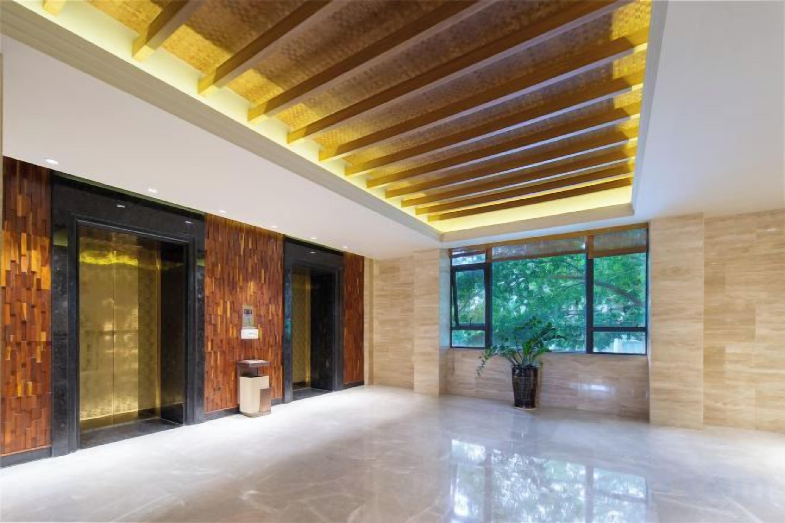Un vestíbulo moderno con piso pulido, paneles de madera y un amplio ventanal con vista a áreas verdes.