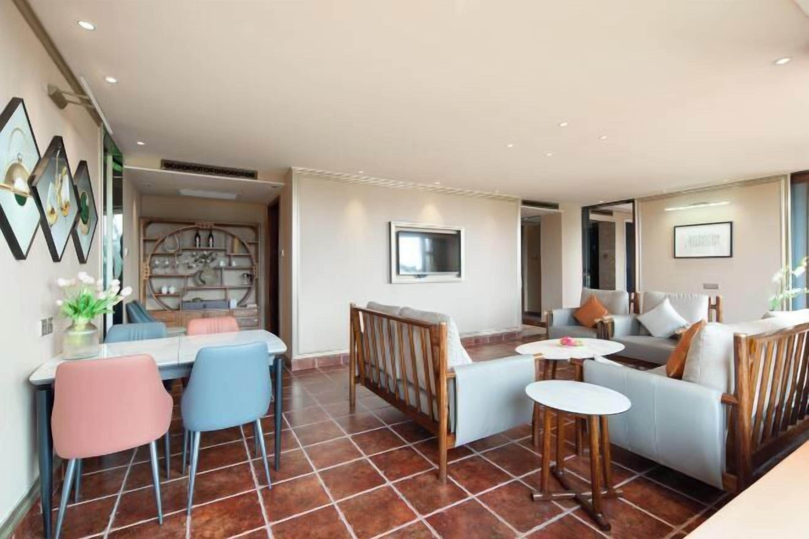 Una sala de estar moderna con comedor, un conjunto de sofás y un televisor montado en la pared.