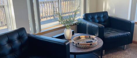 A living room with two black leather sofas, a round coffee table, and a potted plant.