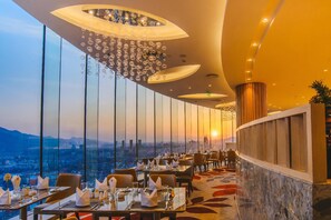 Un restaurante con vistas a la ciudad, diseño de interiores moderno y un comedor con mesas dispuestas para los clientes.