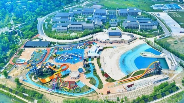 An aerial view of a resort with a water park, multiple buildings, and a large parking area.