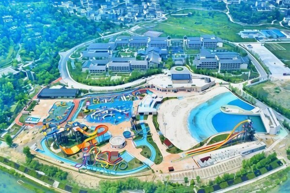 An aerial view of a resort with a water park, multiple buildings, and a large parking area.