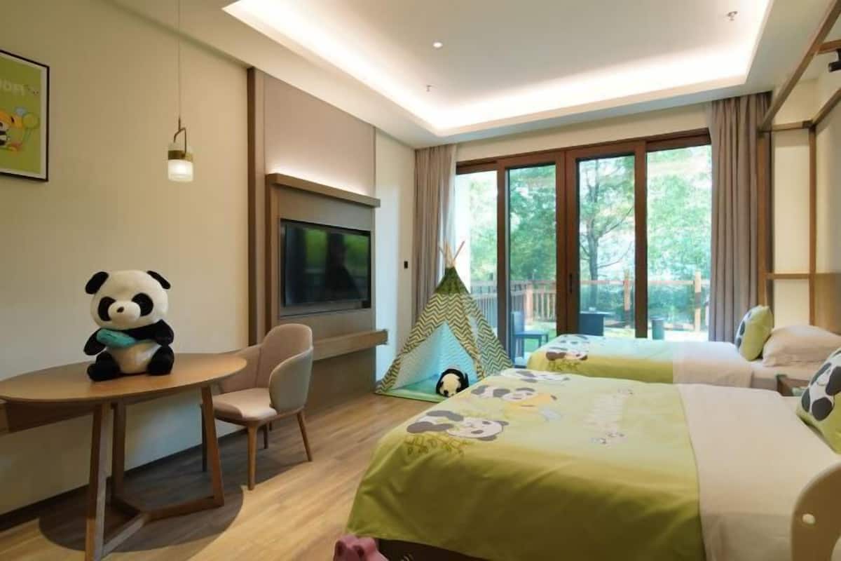 Una habitación de hotel con cama, escritorio, silla, televisor, ventana y una tienda de campaña.