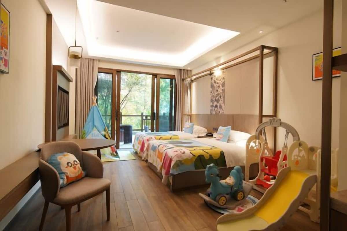 Habitación de hotel con cama, una silla, una mesa, zona de juegos con tobogán y vistas al exterior.