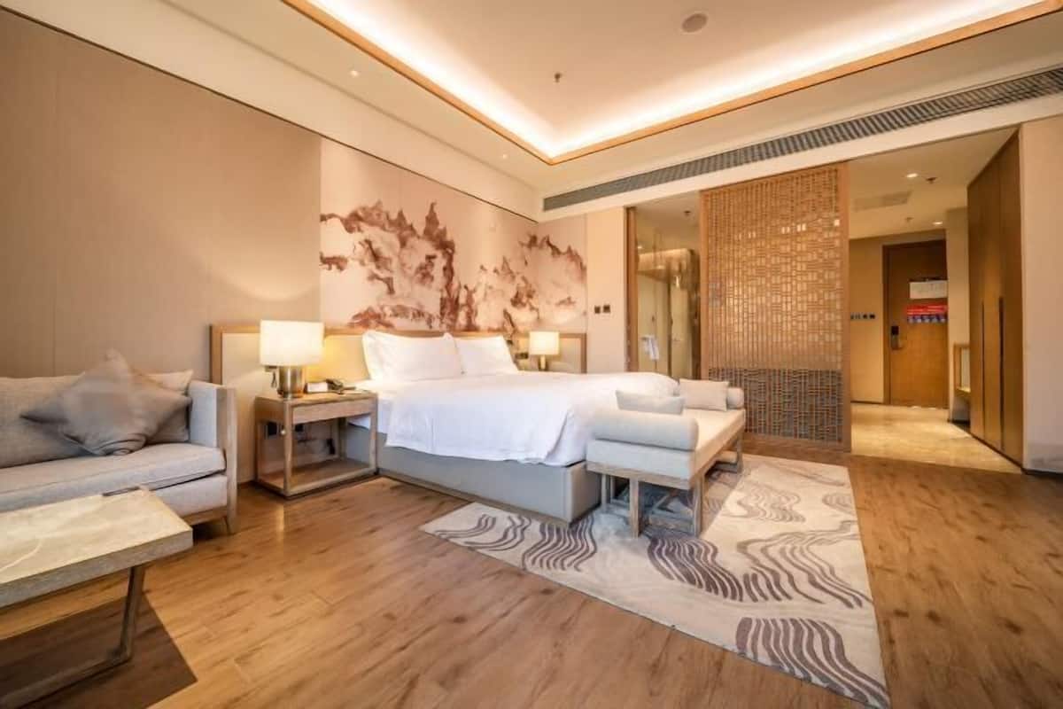 Una habitación de hotel moderna con una cama, mesitas de noche, un sofá y una alfombra estampada.