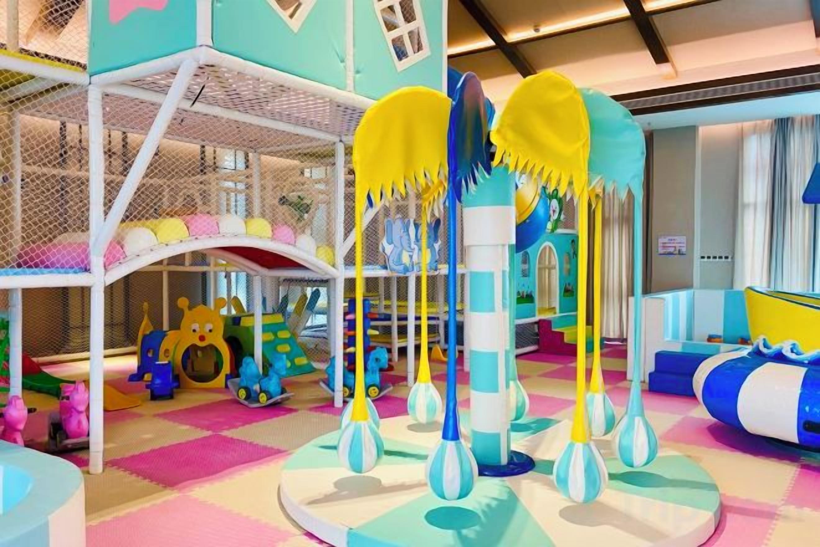 A children's play area with a climbing structure, soft play surfaces, and colorful toys.