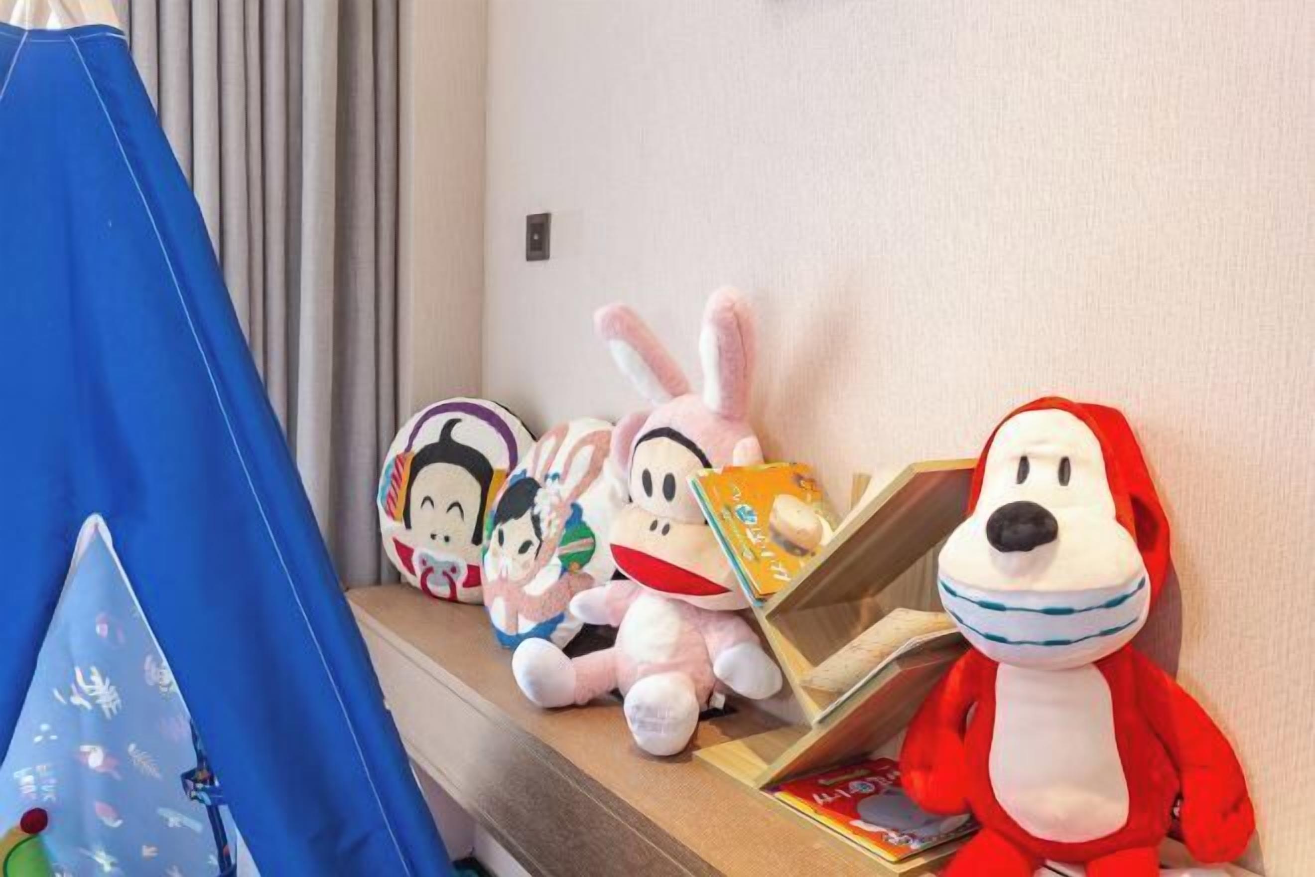 A shelf with plush toys and a small blue tent.