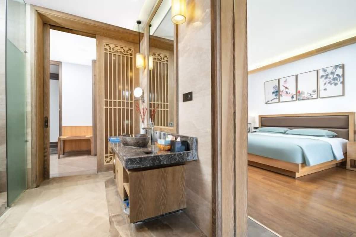 Un dormitorio moderno con una cama de madera, una mesita de noche de mármol y una pequeña zona de estar.
