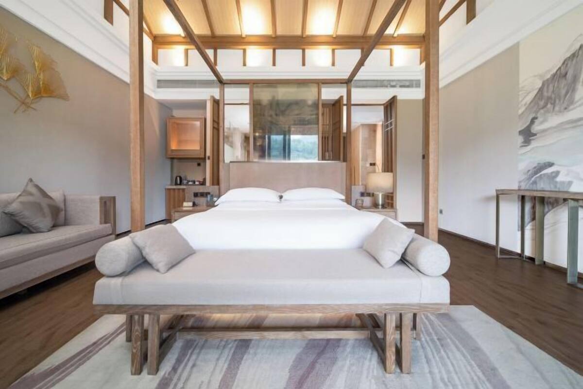 Un dormitorio moderno con una cama grande, cabecera de madera y vistas al exterior.