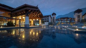 A hotel with a traditional architectural style, featuring a spacious outdoor area with a reflective pool and multiple buildings.