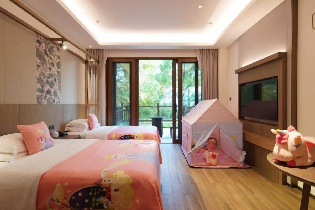 Habitación de hotel con dos camas, una tienda de campaña, un televisor y vistas a zonas verdes.