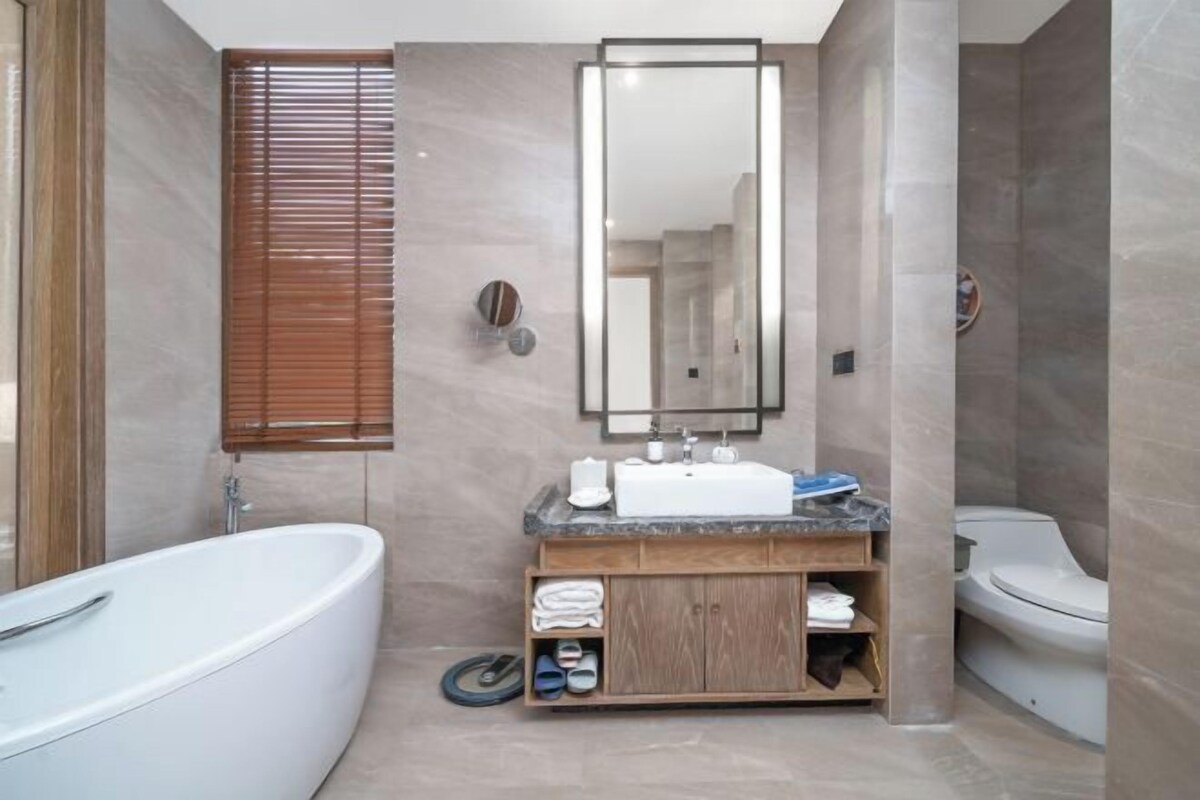 A modern bathroom with a freestanding bathtub, a vanity with a mirror, and a toilet.