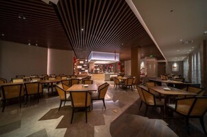Restaurante moderno com pé-direito alto e área de bar central.
