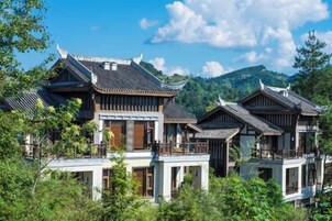 Traditional multi-story buildings with wooden balconies, surrounded by lush greenery and mountains in the background.