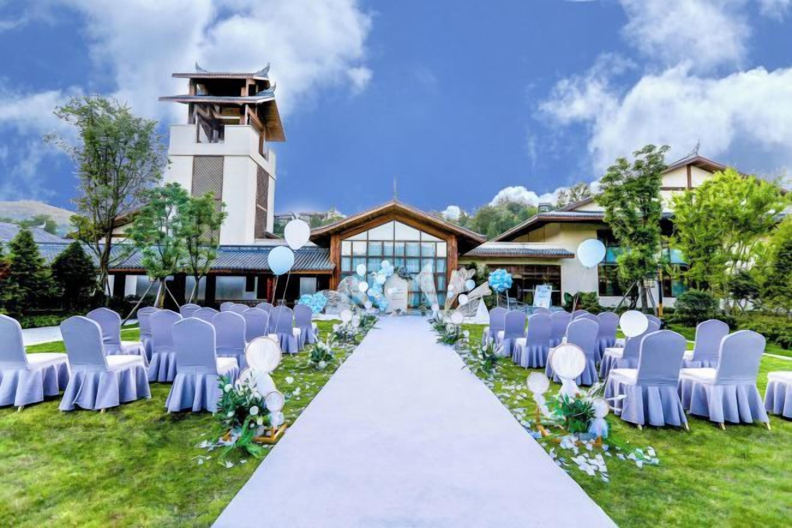 A wedding venue with a central aisle, chairs on either side, and a building in the background.
