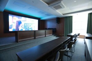 A conference room with a long table, chairs, a large screen, and a speaker. - Qingchuang Hotel (Ziyang)