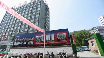 A multi-story building with a large billboard, parked scooters, and a green gate.
