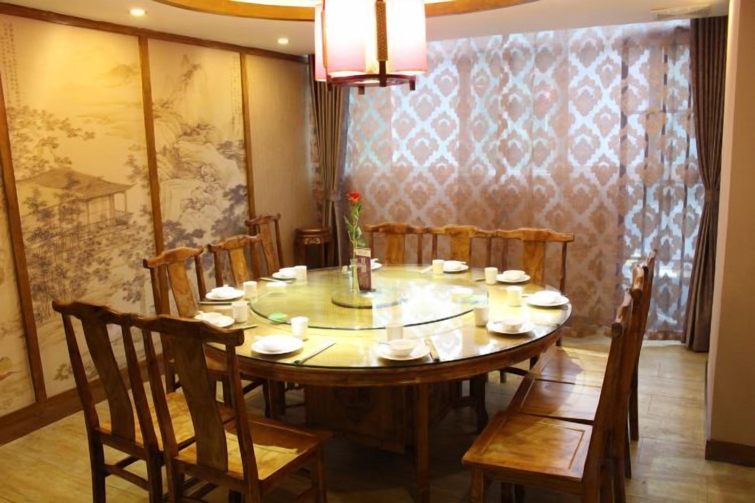 A round dining table with chairs, a glass top, and a vase with flowers.