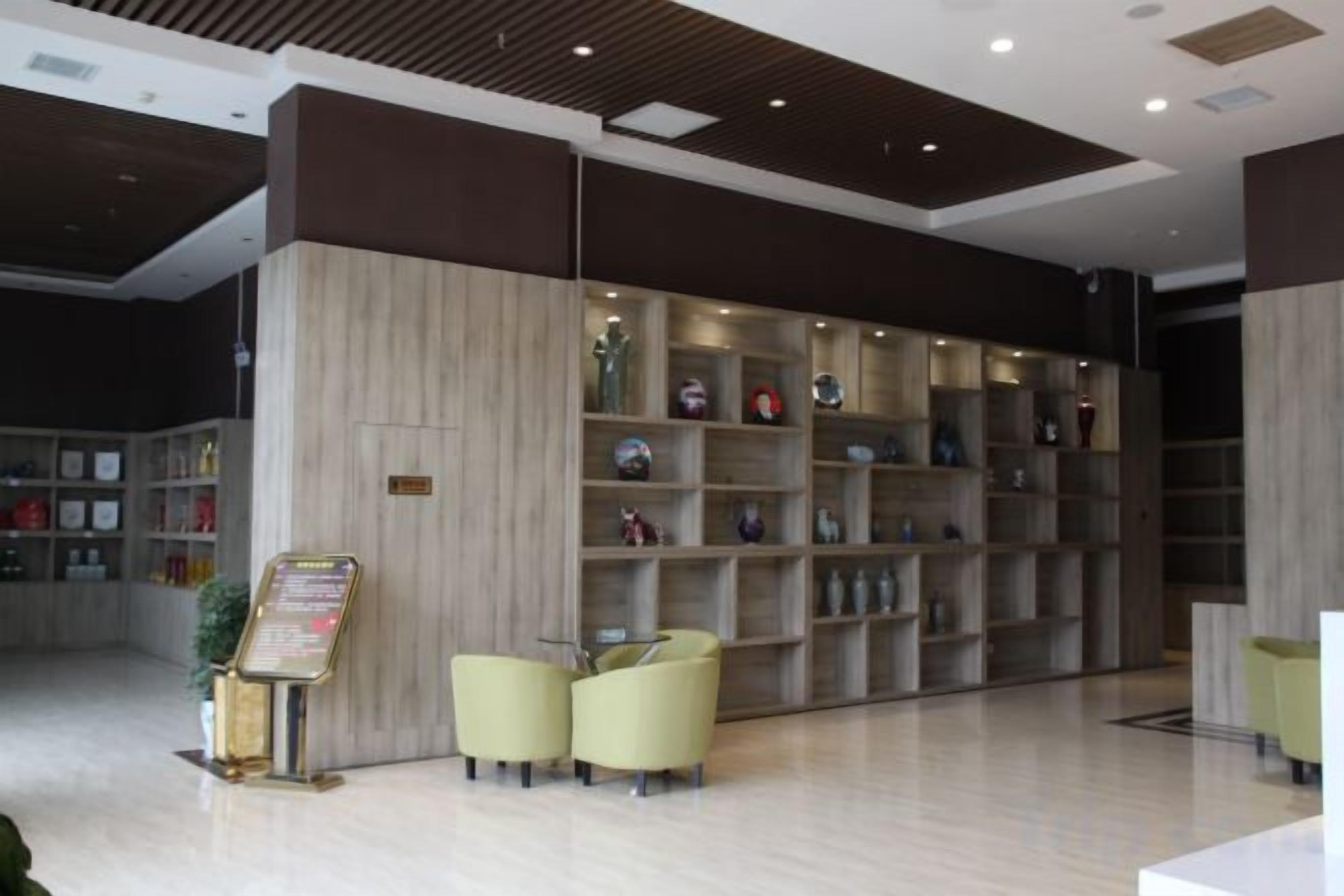 A reception area with a wooden reception desk, a seating area with chairs, and a wall with shelves containing various items.