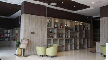 A reception area with a wooden reception desk, a seating area with chairs, and a wall with shelves containing various items.
