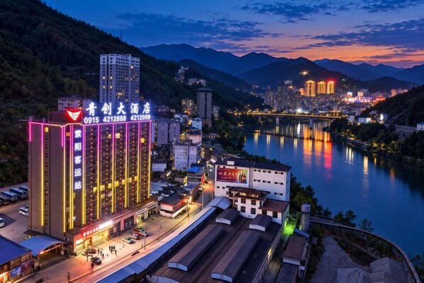 A multi-story hotel with a prominent sign, located near a river with a bridge in the background.