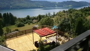 A wooden deck with a red roof overlooking a lake and mountains. - Superior apartment with 2 balconies with lake and mountain view (Starfach)