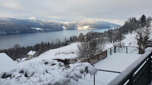 A snow-covered landscape with a lake, mountains, and a wooden fence. - Superior apartment with 2 balconies with lake and mountain view (Starfach)