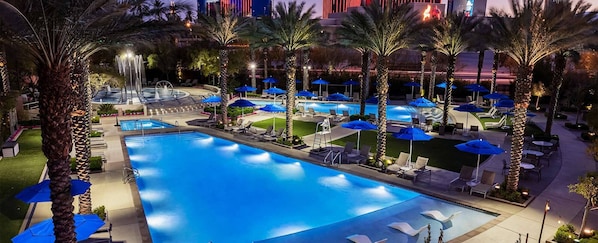 Relax by the pool surrounded by palm trees and lounge areas with sun loungers and umbrellas.