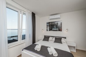 Een moderne hotelkamer met een groot bed, uitzicht op zee en een airconditioning.