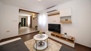 Una sala de estar moderna con una mesa de centro redonda, un televisor de pantalla plana y estantes empotrados.