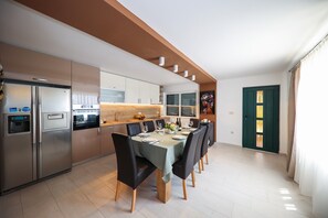 Une cuisine moderne avec un coin repas, des appareils électroménagers en acier inoxydable et une grande fenêtre.