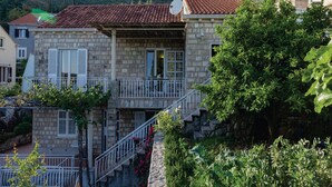 A stone building with a red-tiled roof, a balcony, and a satellite dish.