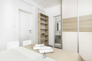 A modern bedroom with a bed, a wardrobe, and a built-in shelf unit.