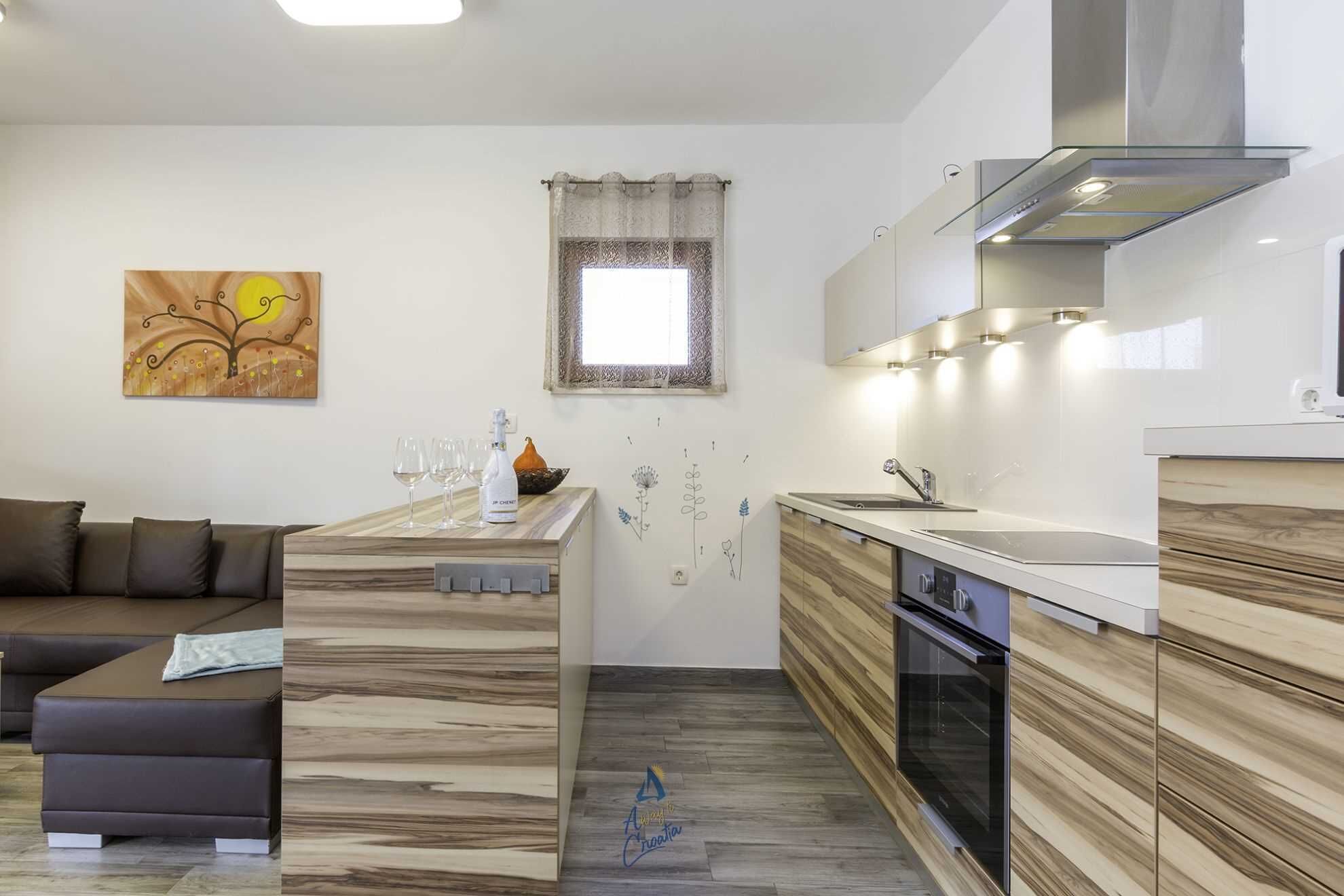 Una cocina moderna con horno empotrado, un comedor con isla de madera y una sala de estar con sofá marrón.