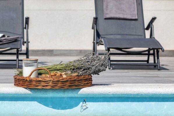 A poolside setting with a wicker basket containing lavender and a milk jug.
