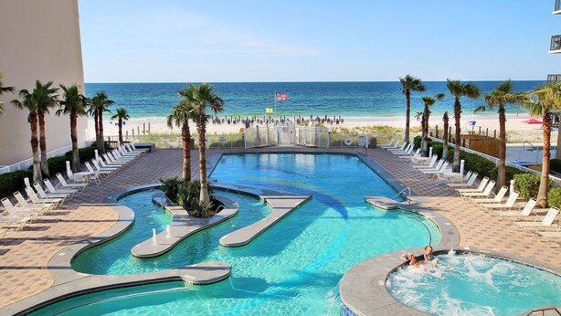 Ein Poolbereich mit Blick auf den Strand, Liegestühle und Palmen.